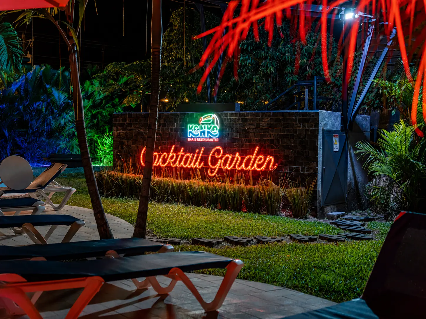 Cocktail Garden neon sign glowing over the lawn at night