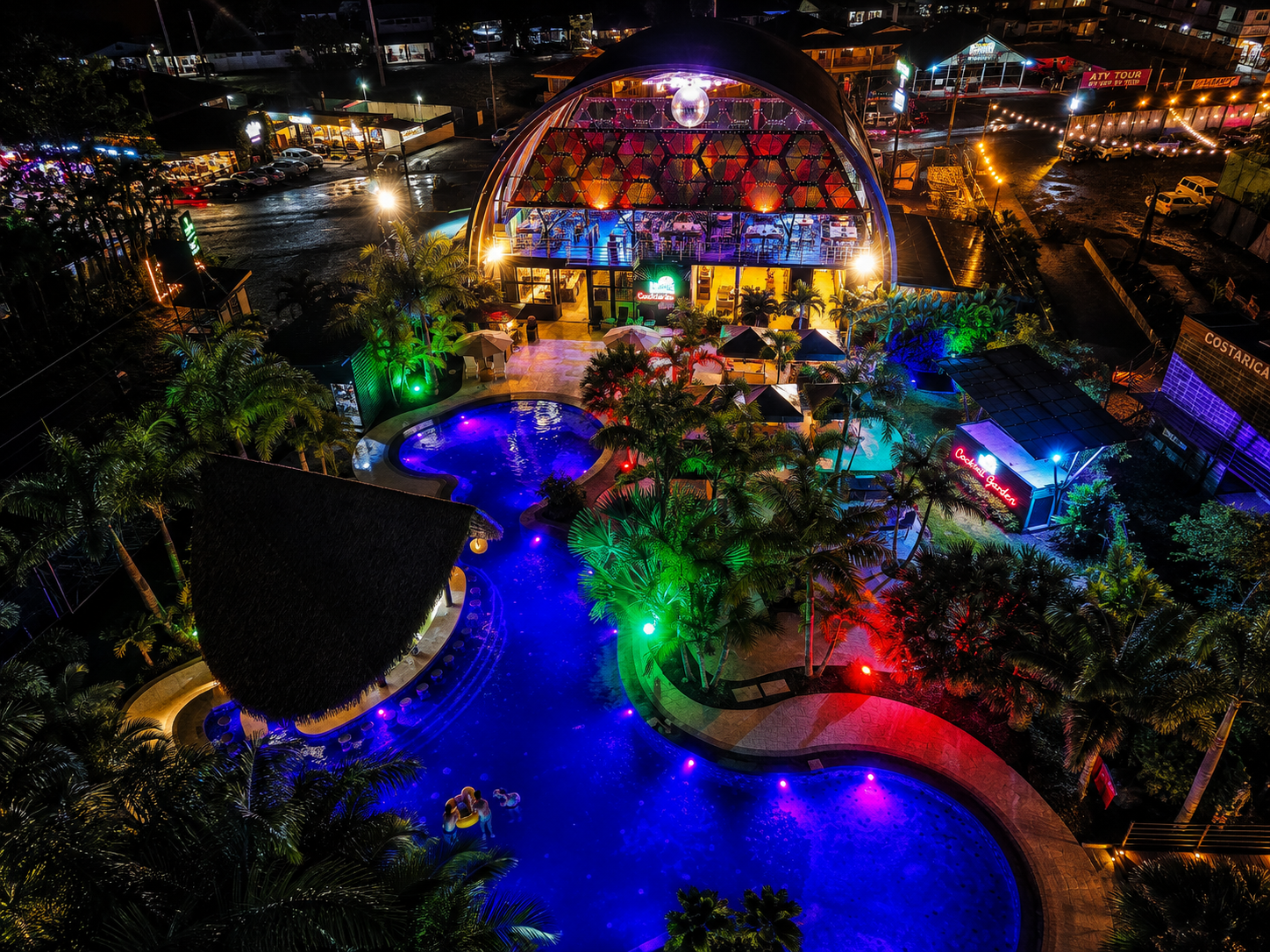 Aerial night view of the illuminated pool, palms and the Kenko dome